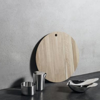 BORDA Round Oak Cutting Board next to stainless steel kitchen accessories