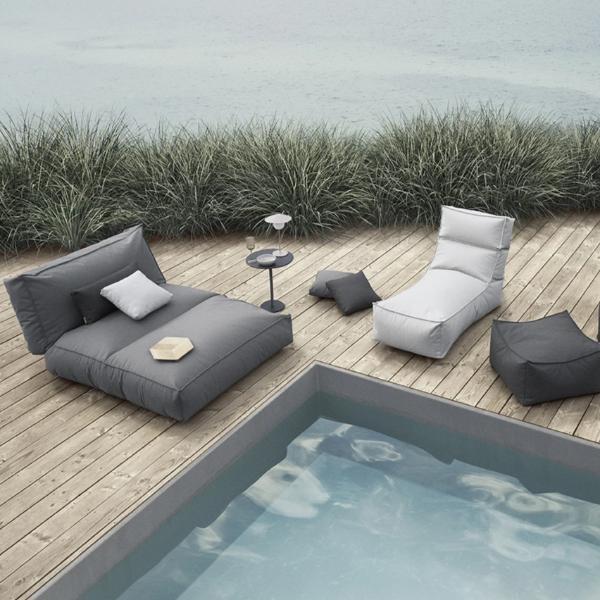 Outdoor furniture and side table next to a modern pool on a wooden patio 