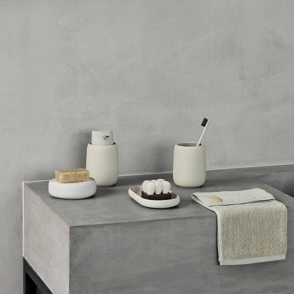 Concrete countertop displaying blomus SONO bathroom set in an industrial modern setting