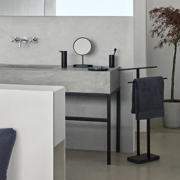 Black metal freestanding towel stand in a minimalist bathroom setting
