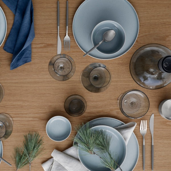 SABLO Stoneware Stone color ceramic dinnerware with MAXIME flatware, BELO smoke color wine glasses and ALPHA Decanter arranged on a modern wood table for elegant dining