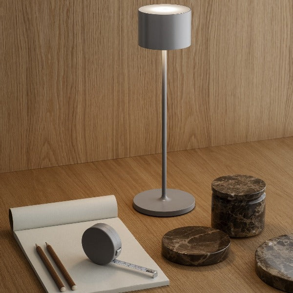 Modern wooden work desk area with tape measure and note pad lit by an LED rechargeable lamp