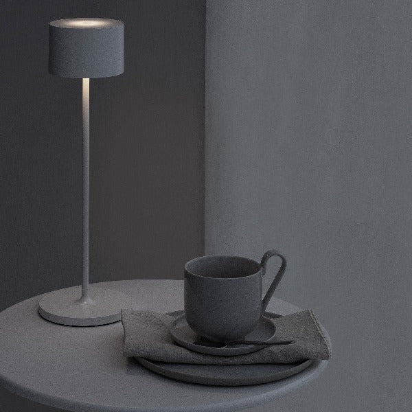 Dark setting with coffee cup and dim light from a small table lamp