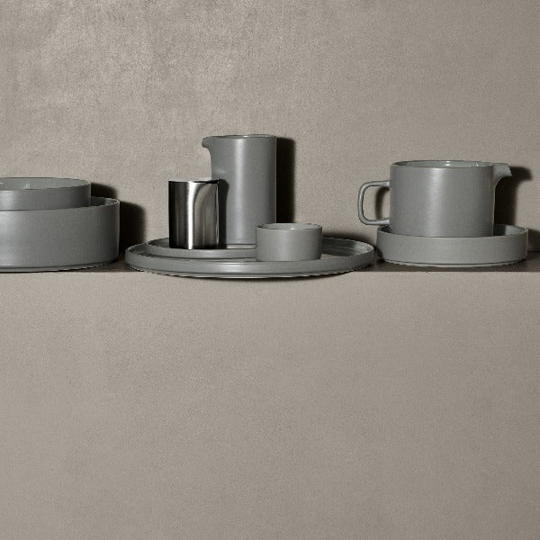 Scandinavian inspired PILAR stoneware with a matte mirage grey exterior arranged casually upon a concrete ledge 